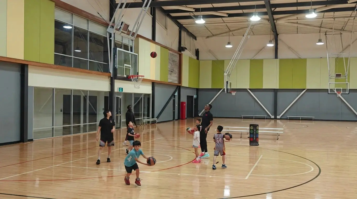 A dynamic indoor basketball court scene at First Pick Academy where children and coaches engage in skill-building exercises, illustrating the academy's expertise in neuro-coaching for youth.