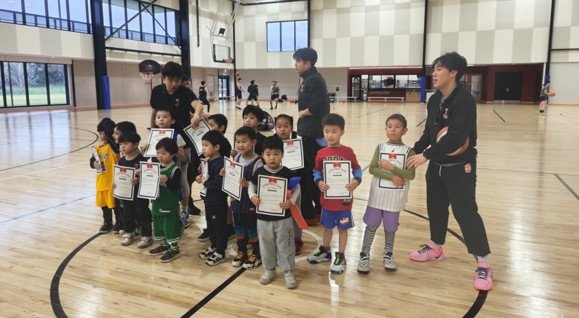 Young players at First Pick Basketball holding certificates during the holiday camp award ceremony in Melbourne indoor court.