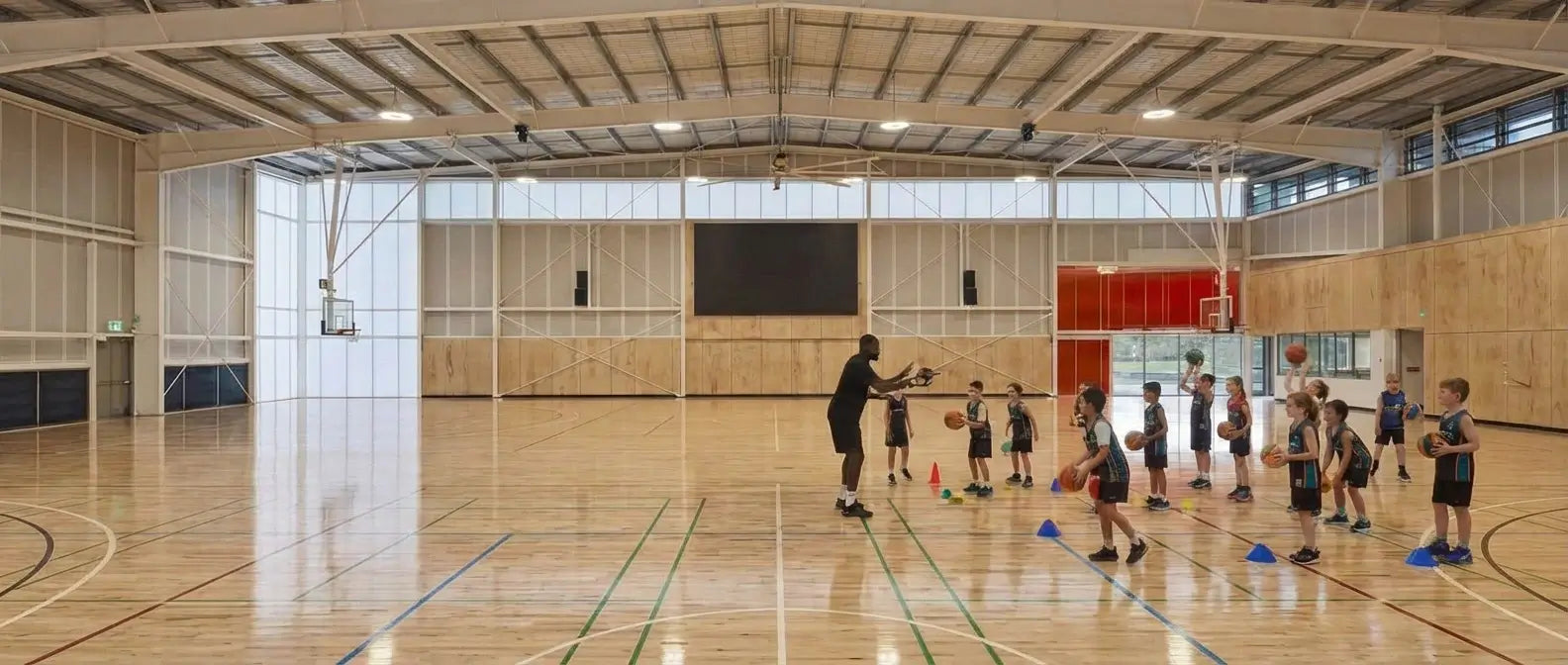 Junior basketball coaching session at First Pick Academy's Wheelers Hill campus, featuring professional blue courts and serving families in the Mt Waverley and Monash areas.