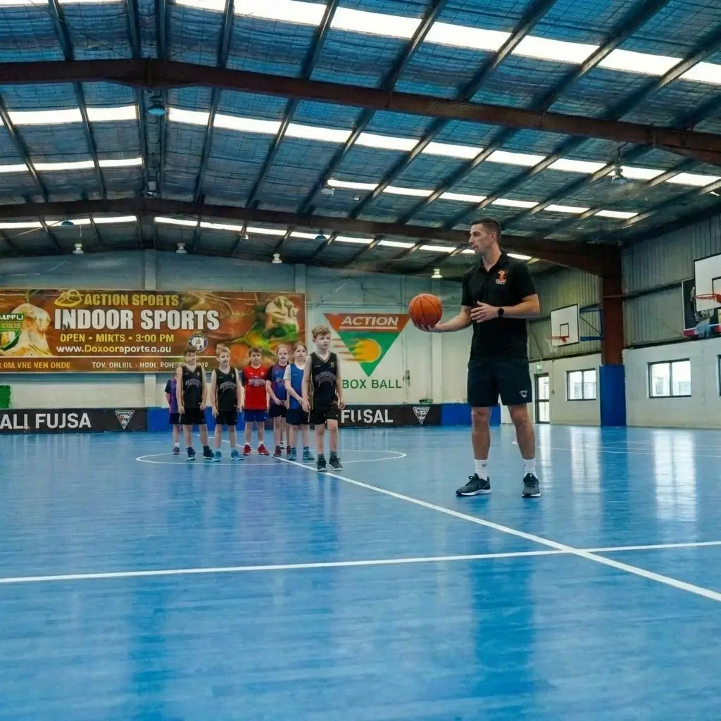 Professional basketball coaches providing expert guidance and technical feedback to junior athletes on the blue courts at First Pick Academy’s Box Hill South campus.