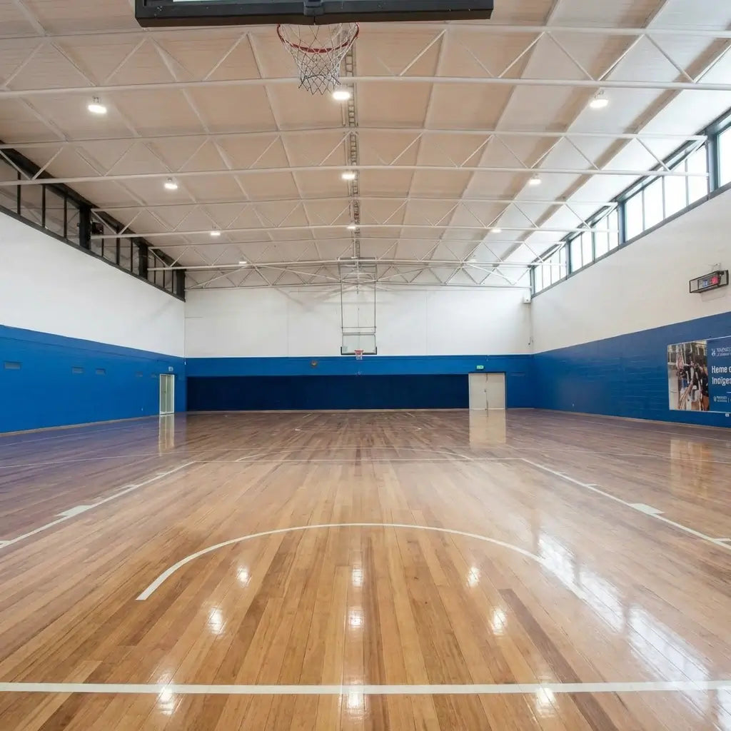 Close-up shot of high-traction polished wooden basketball court at First Pick Clayton, highlighting the professional surface for athlete safety and explosive power.