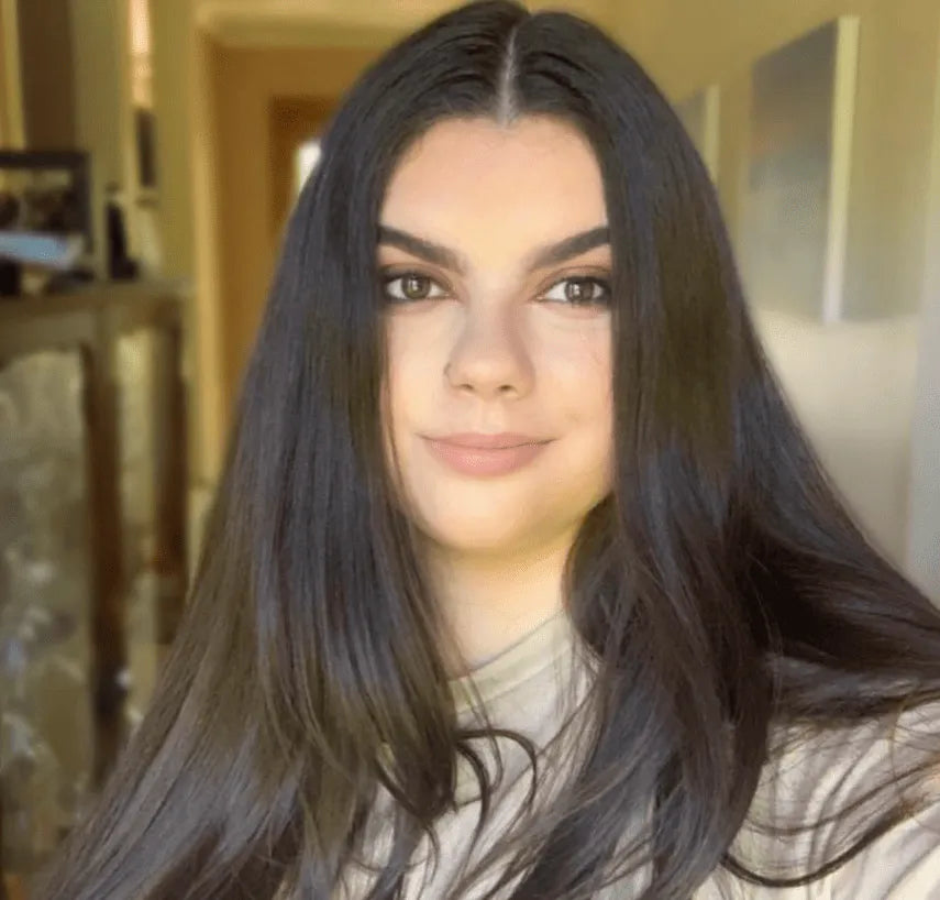 A candid, high-end lifestyle shot of Sarah, a Monash parent, smiling while watching her son’s 5+3 basketball training from the sidelines at a bright, modern Melbourne stadium.